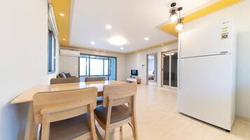 A modern kitchen with a white refrigerator, wooden chairs, and a dining table.