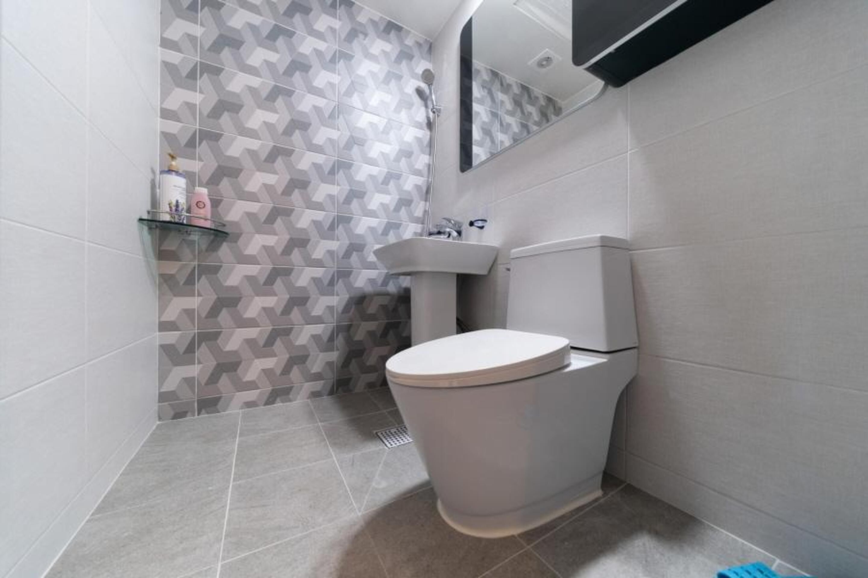A modern bathroom with a toilet, sink, and shower.