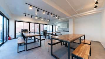 Una cocina amplia y moderna con grandes ventanales, una isla central y un comedor con mesas y bancos de madera.
