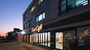 A building with a 'Sun Cafe' sign, large windows, and a paved area in front. - Busan Haeoream Pension (Busan)