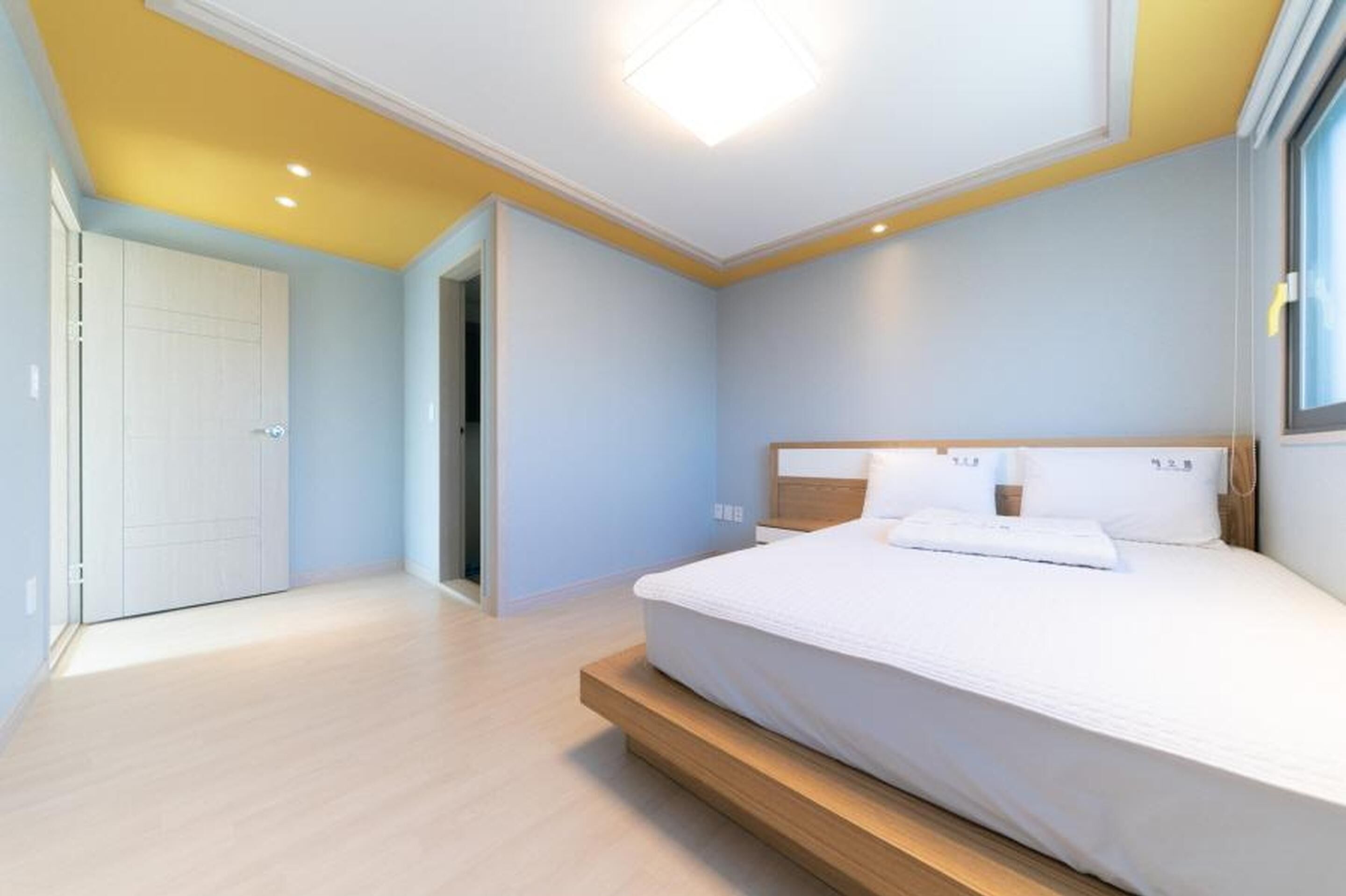 A bedroom with a bed, a wooden headboard, and a door leading to another room.