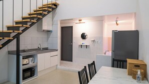 Une cuisine moderne avec un escalier en bois, un four encastré et un coin repas comprenant une table et des chaises.