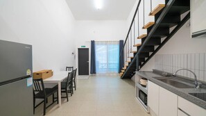 Eine moderne Küche mit integriertem Kühlschrank, eine Essecke mit Tisch und Stühlen sowie eine Treppe mit Holzbodenstufen.