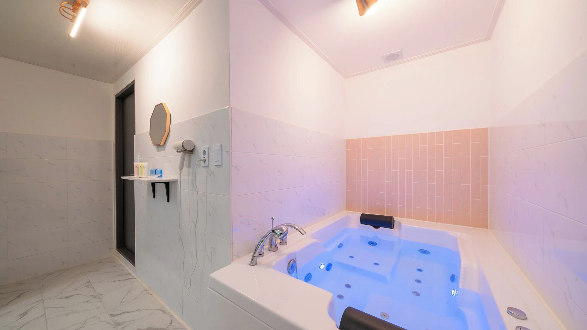 A modern bathroom with a large bathtub, a mirror, and a shelf with toiletries.