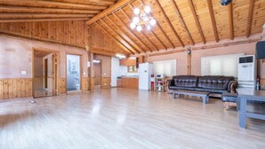 A spacious living area with wooden floors and a high ceiling, featuring a sofa, a table, and a kitchen area in the background. - Yangpyeong Santa Pension (Yangpyeong)