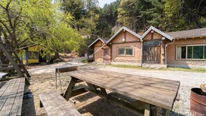 A rustic cabin with a wooden deck, a picnic table, and a stone foundation. - Yangpyeong Santa Pension (Yangpyeong)