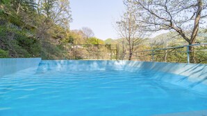 A clear blue swimming pool with a metal railing, surrounded by trees and a mountainous backdrop. - Yangpyeong Santa Pension (Yangpyeong)