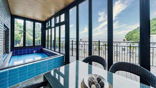 A balcony with a pool, a table, and chairs. - Namhae Yanghwa Seaside Pension (Namhae)