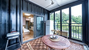A room with a sliding glass door leading to a kitchen, a round wooden table with a bowl, and a bench. - Namhae Yanghwa Seaside Pension (Namhae)