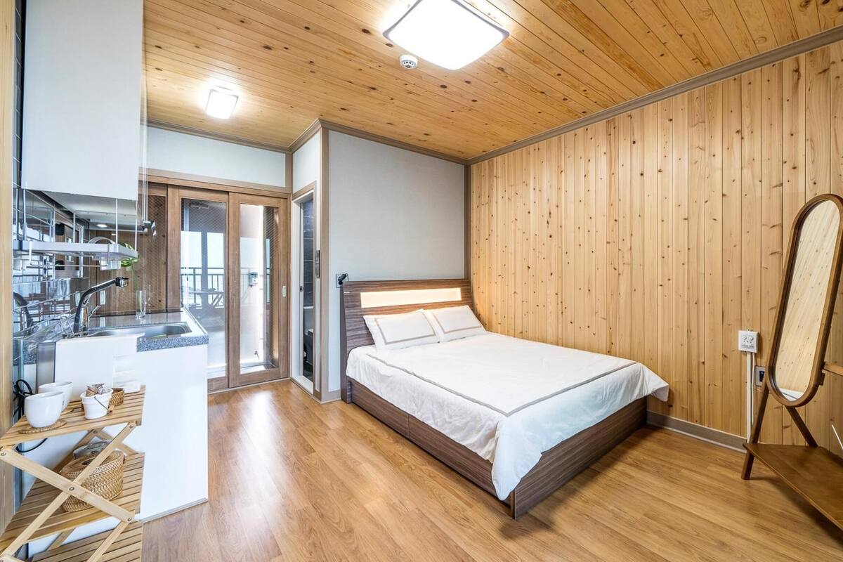 Une chambre avec un plafond en bois, un lit avec une literie blanche, une armoire en bois et un grand miroir.