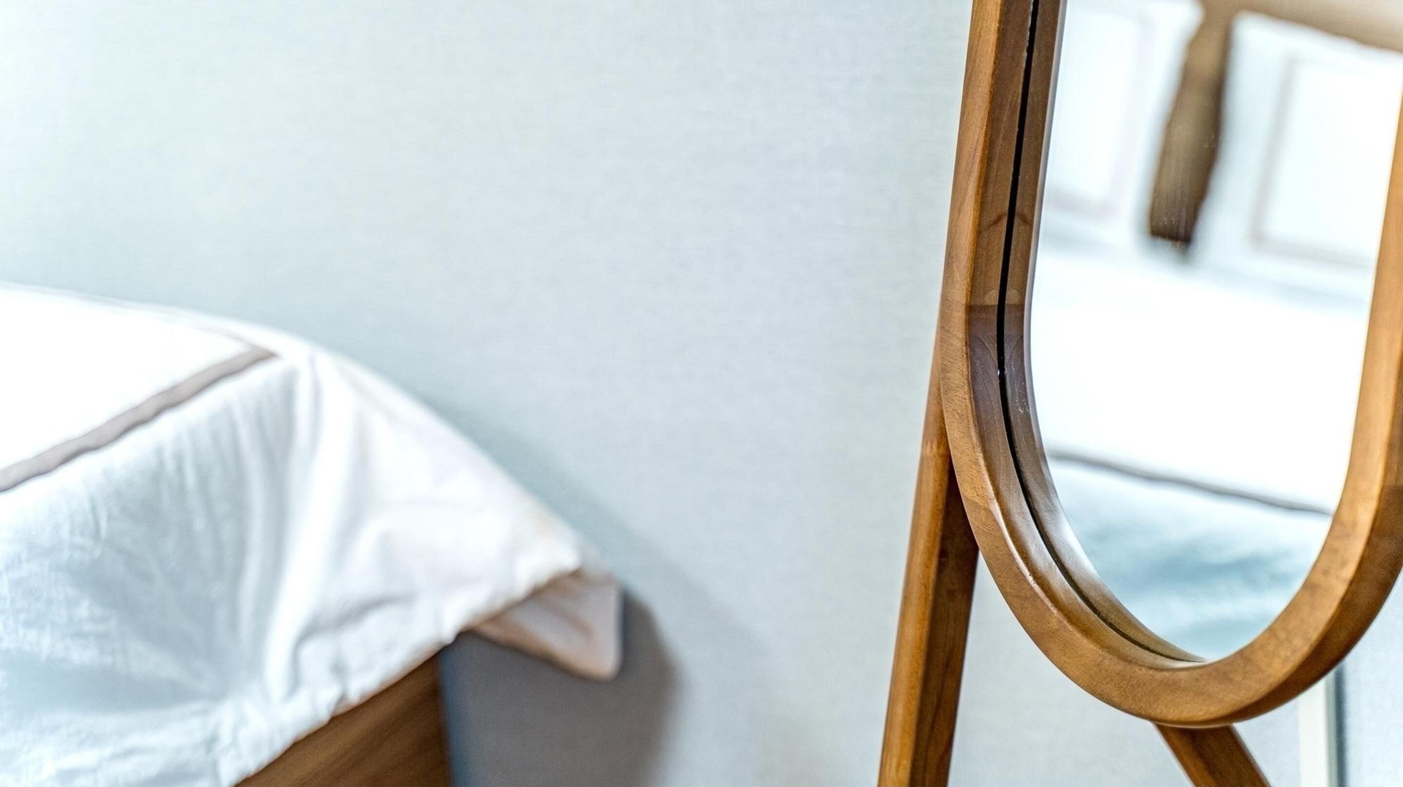 Una silla de madera con respaldo curvo y una cama blanca con edredón blanco.