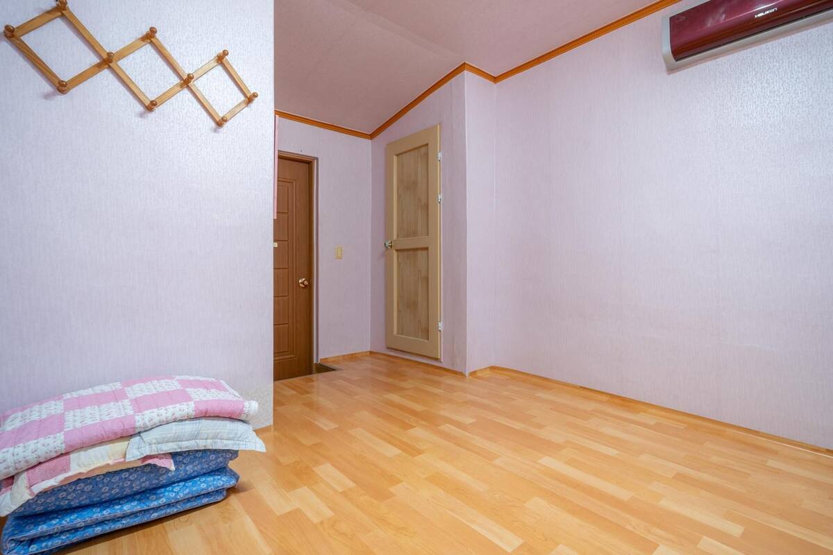 Ein Zimmer mit Holzboden, einer Tür und einem Stapel gefalteter Decken.