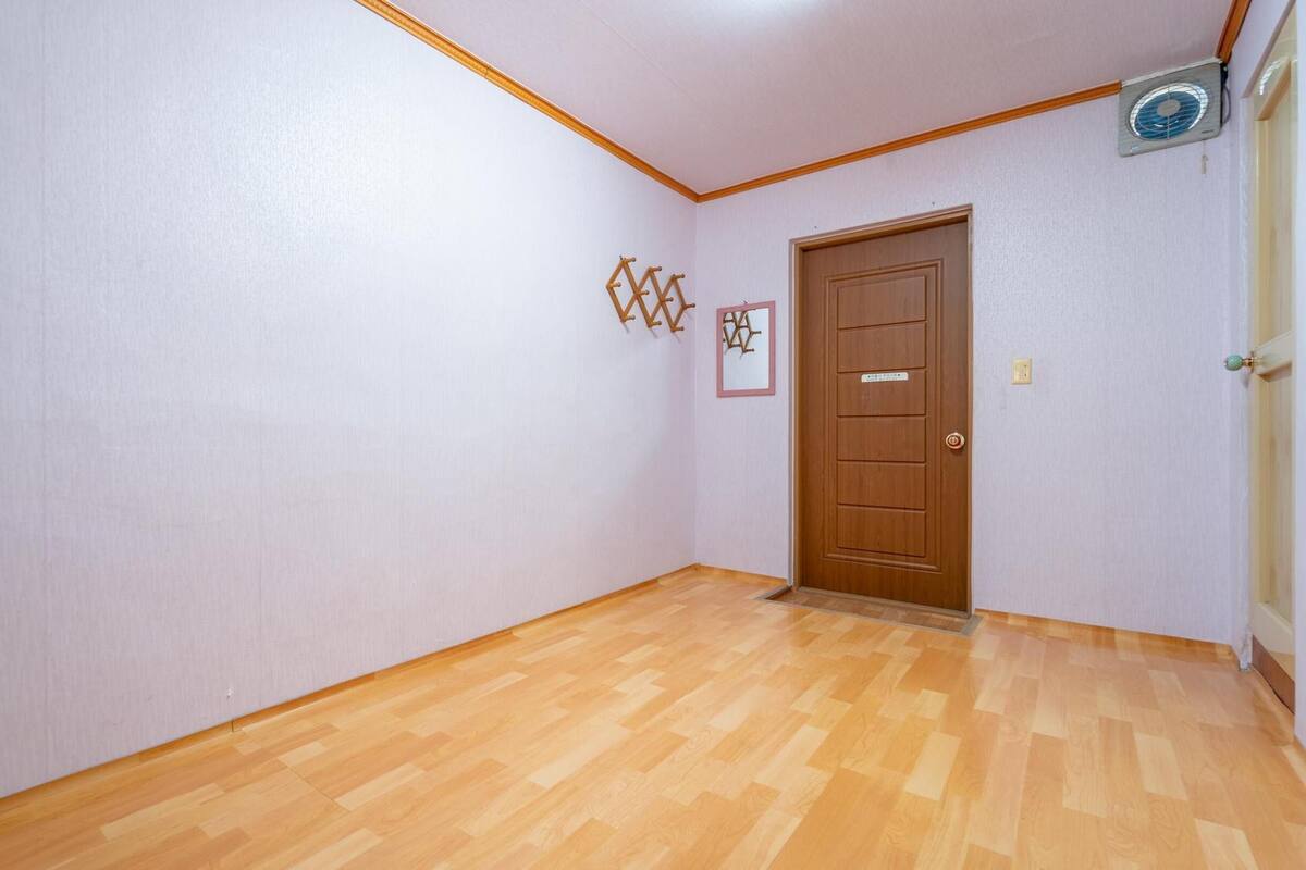 Ein Korridor mit Holzboden, einer Holztür und einem Deckenventilator.