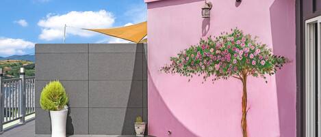 Un edificio rosa con un árbol pintado y una pequeña planta en maceta.