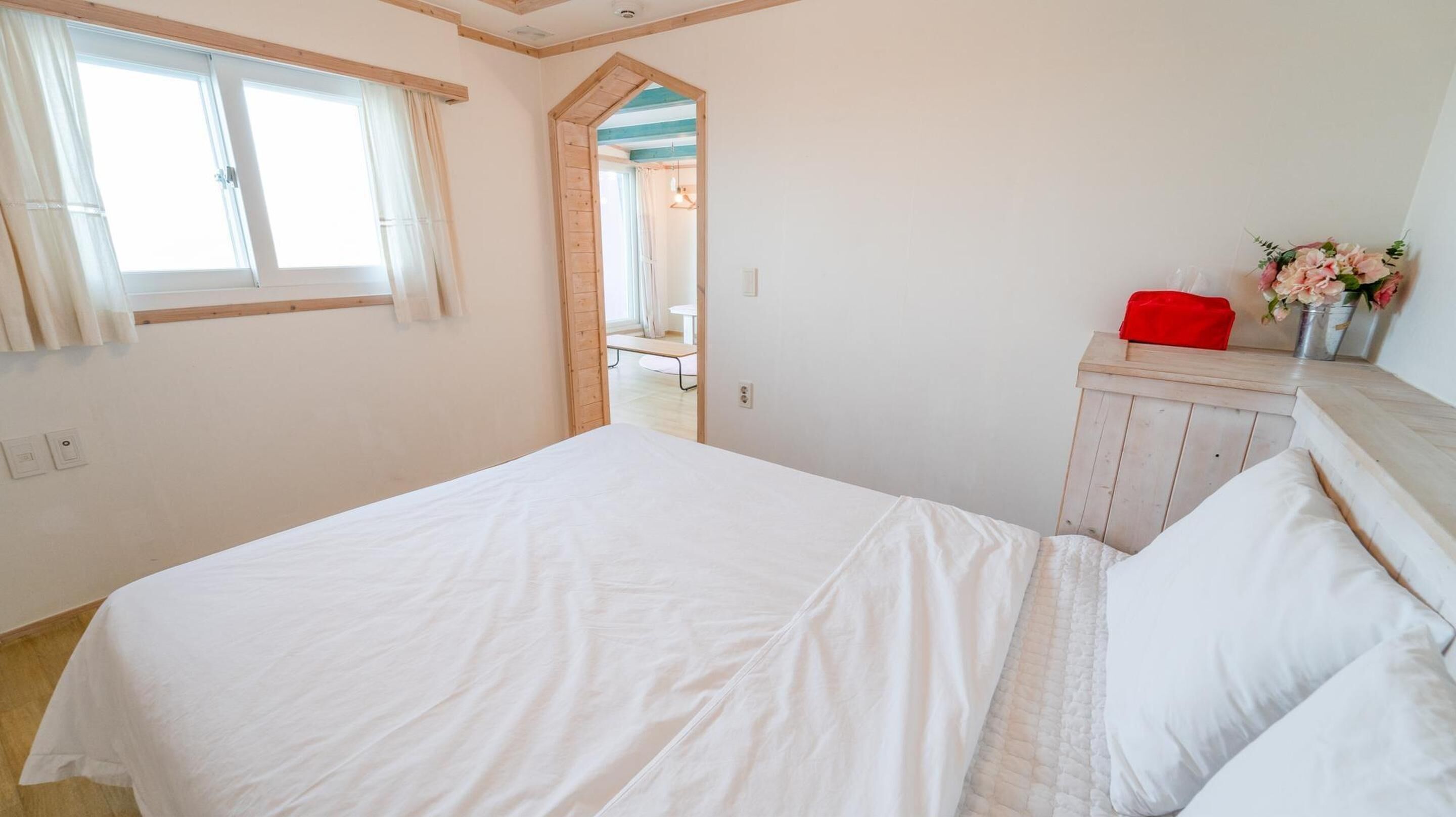 A bedroom with a large bed, a wooden wardrobe, and a window with curtains.