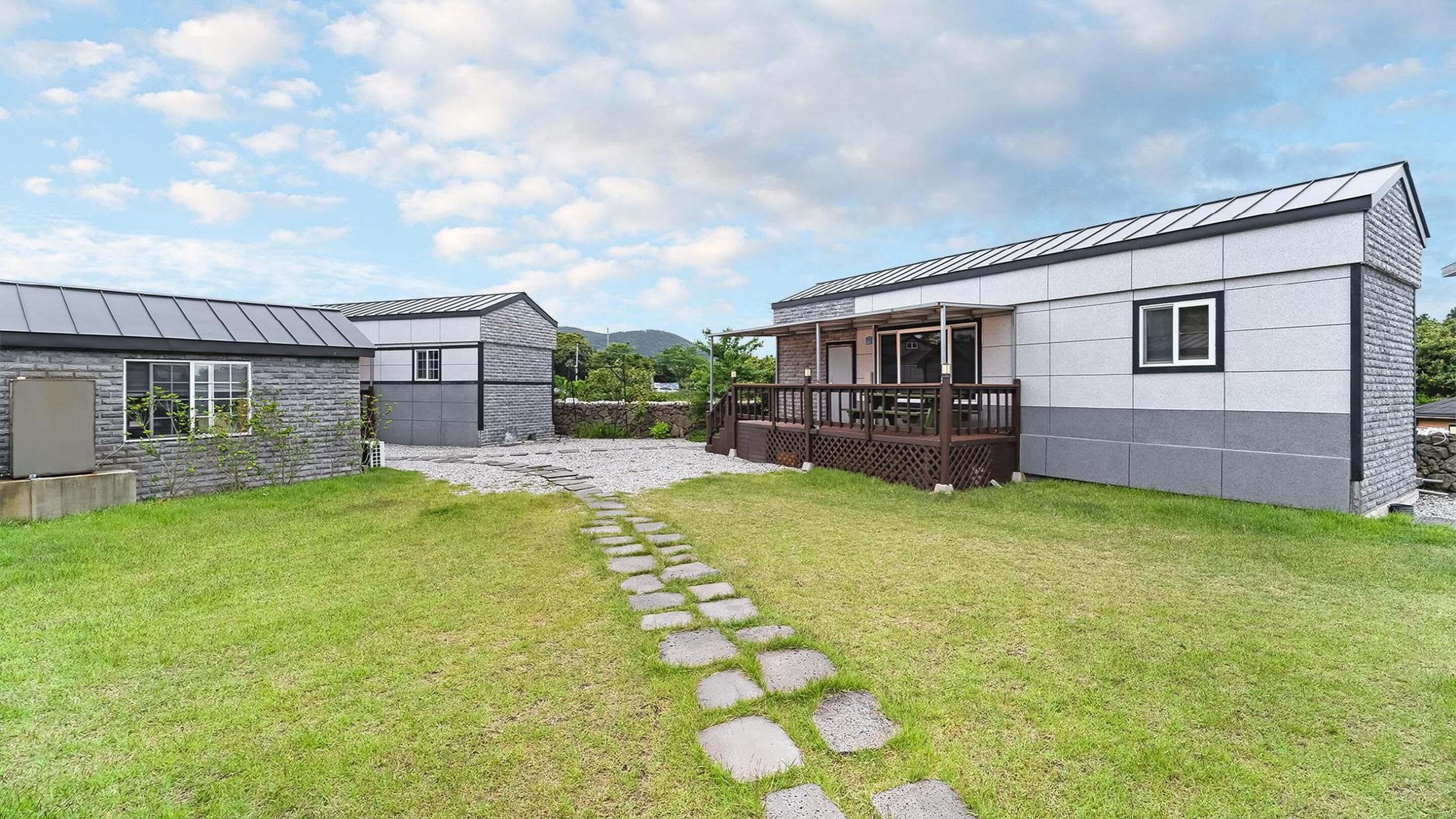Uma casa moderna de dois andares com fachada de pedra e varanda coberta.