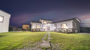 A two-story house with a stone exterior, a front porch, and a paved driveway leading to the entrance. - Jeju Bijalim Pension (Jeju City)