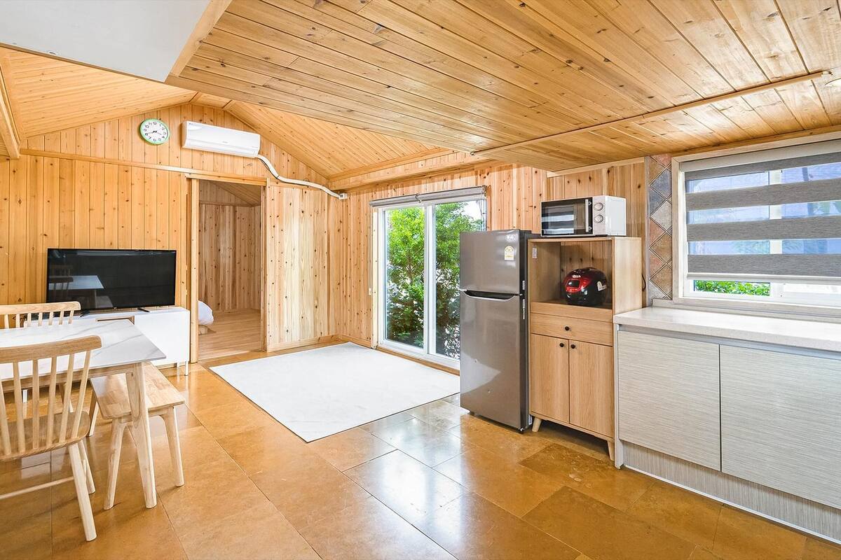 A wooden cabin with a kitchen, dining area, and a sleeping area.