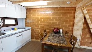 Une cuisine de taille réduite avec des meubles blancs, un plan de travail en granit et une table à manger avec des chaises.