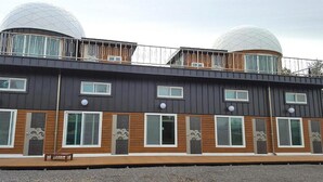 Un bâtiment moderne doté de deux grandes coupoles, d’un balcon avec des rampes en métal et de nombreuses fenêtres agrémentées de détails en bois.