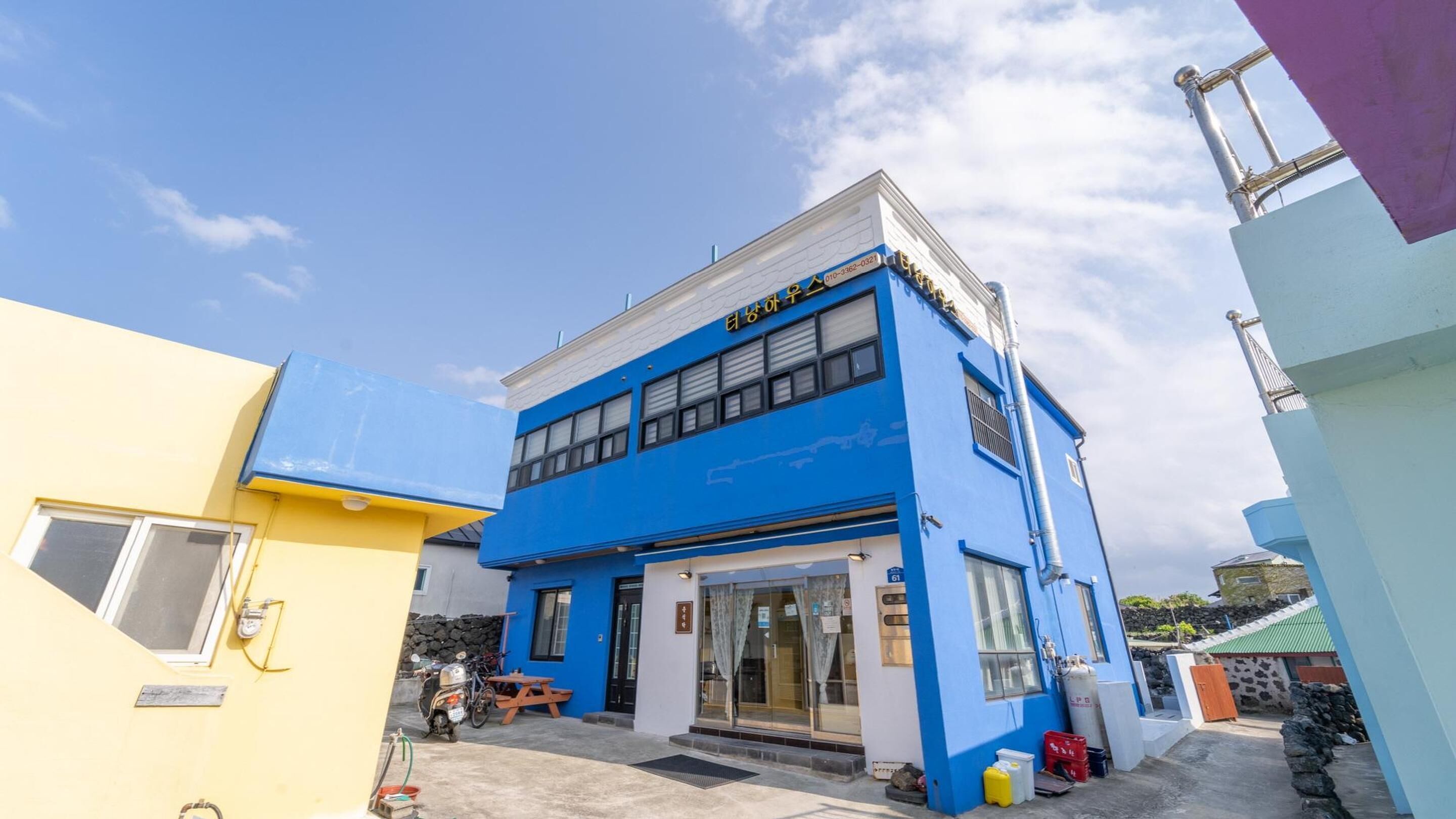 A two-story building with a blue facade and a yellow building adjacent to it.