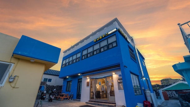 A two-story building with a blue facade and a sign in Korean. - Jeju Tunanghouse Pension (Jeju City)