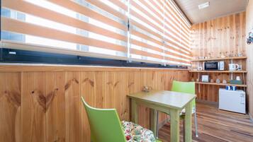 Una cocina compacta con paredes de madera, una pequeña mesa de comedor y un microondas.