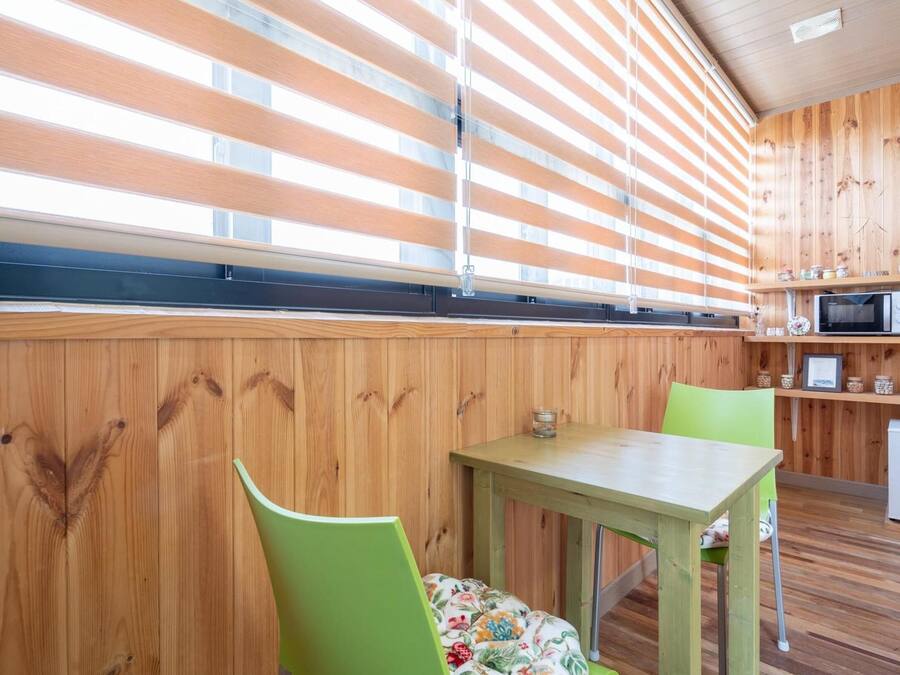 Una cocina compacta con paredes de madera, una pequeña mesa de comedor y un microondas.