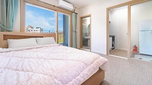 A hotel room with a bed, a bathroom, and a view of a building outside. - Samcheok Aramaru Pension (Samcheok)