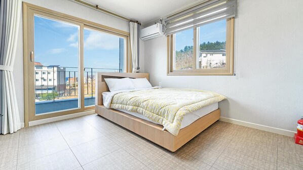 A bedroom with a bed, large windows, and an air conditioning unit. - Samcheok Aramaru Pension (Samcheok)