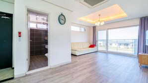 A modern apartment with a bathroom, a sofa, and a large window. - Jeju Byeoleuldameunbaramarae Pension (Jeju City)