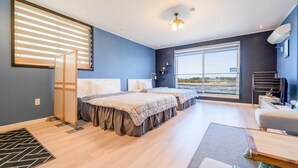 Un dormitorio moderno con dos camas, ventanas amplias y vistas al exterior.