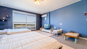 Una habitación de hotel moderna con dos camas, televisión y un ventanal amplio con vistas al exterior.