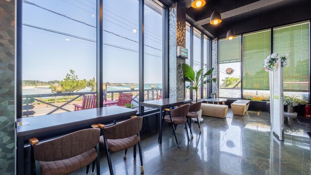 Un área de estar interior moderna con amplios ventanales que dan a una playa, con mobiliario cómodo y un diseño limpio y contemporáneo.