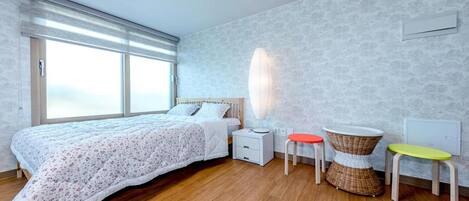 A bedroom with a large bed, a nightstand, a lamp, and two stools.