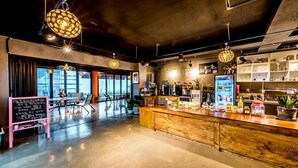 Um café moderno com balcão de madeira, área de estar e grandes janelas.