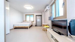 Ein modernes Hotelzimmer mit Bett, Fernseher, kleinem Tisch und einer Tür.