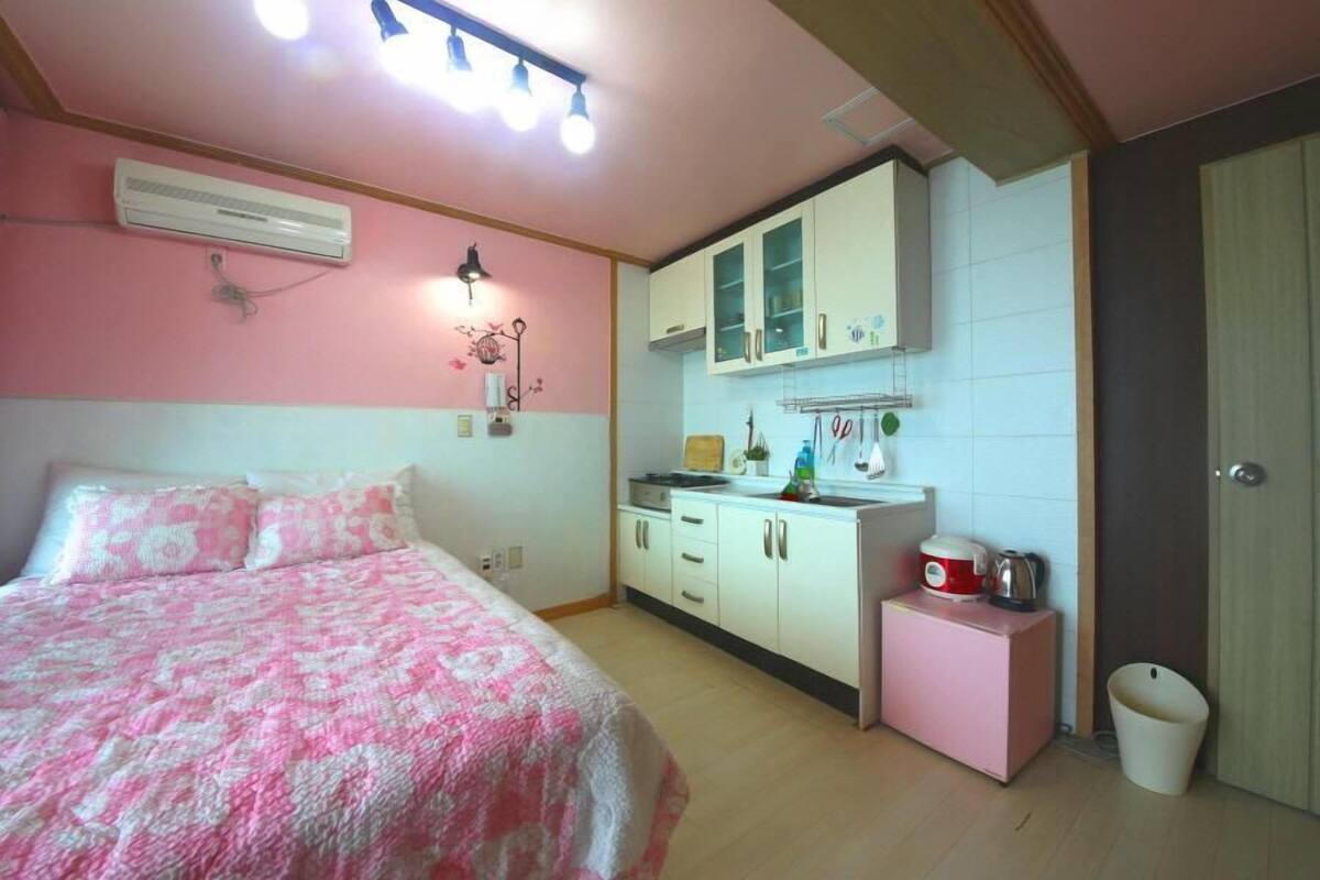 Un dormitorio con cama, una kitchenette pequeña y un baño.