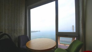 A room with a large window, a round table, and two chairs. - Jeju Syagaluibada Pension (Jeju City)