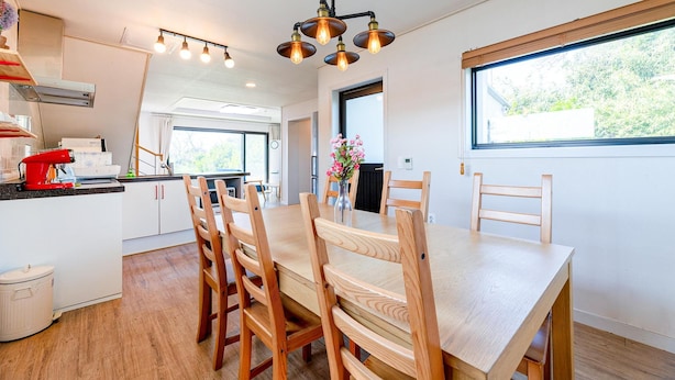 Une cuisine moderne avec des meubles en bois, un batteur rouge et un coin repas comprenant une table et des chaises en bois.