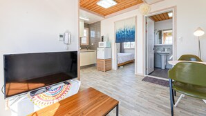 Une chambre moderne équipée d’un téléviseur à écran plat, d’une table en bois et d’une chaise verte.