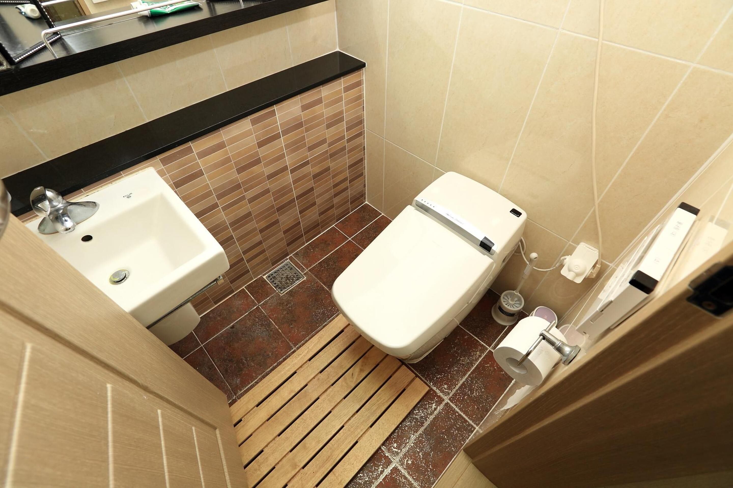 A small bathroom with a sink, toilet, and a wooden floor.