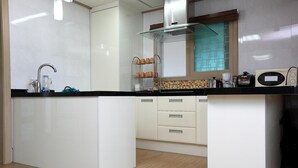 Une cuisine moderne dotée d’un îlot central, de meubles blancs, d’un plan de travail noir et d’une fenêtre offrant une vue agréable.