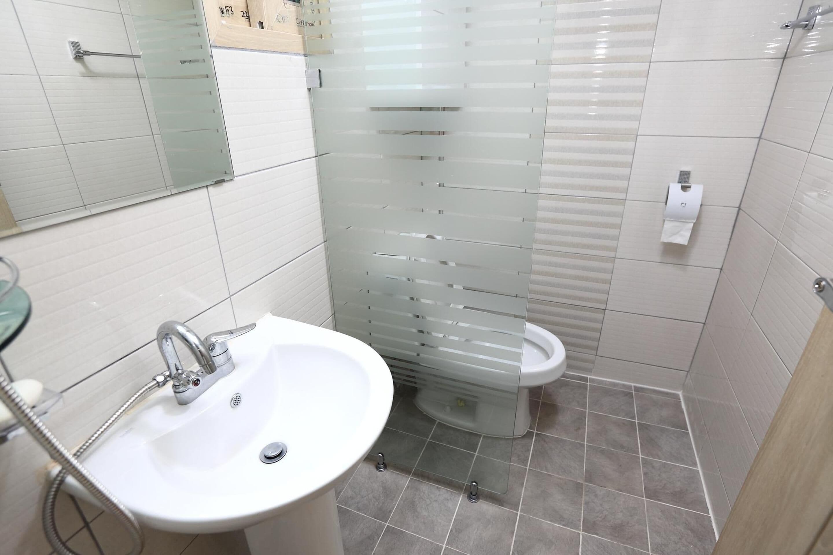 A bathroom with a white sink, a glass shower enclosure, and a toilet.