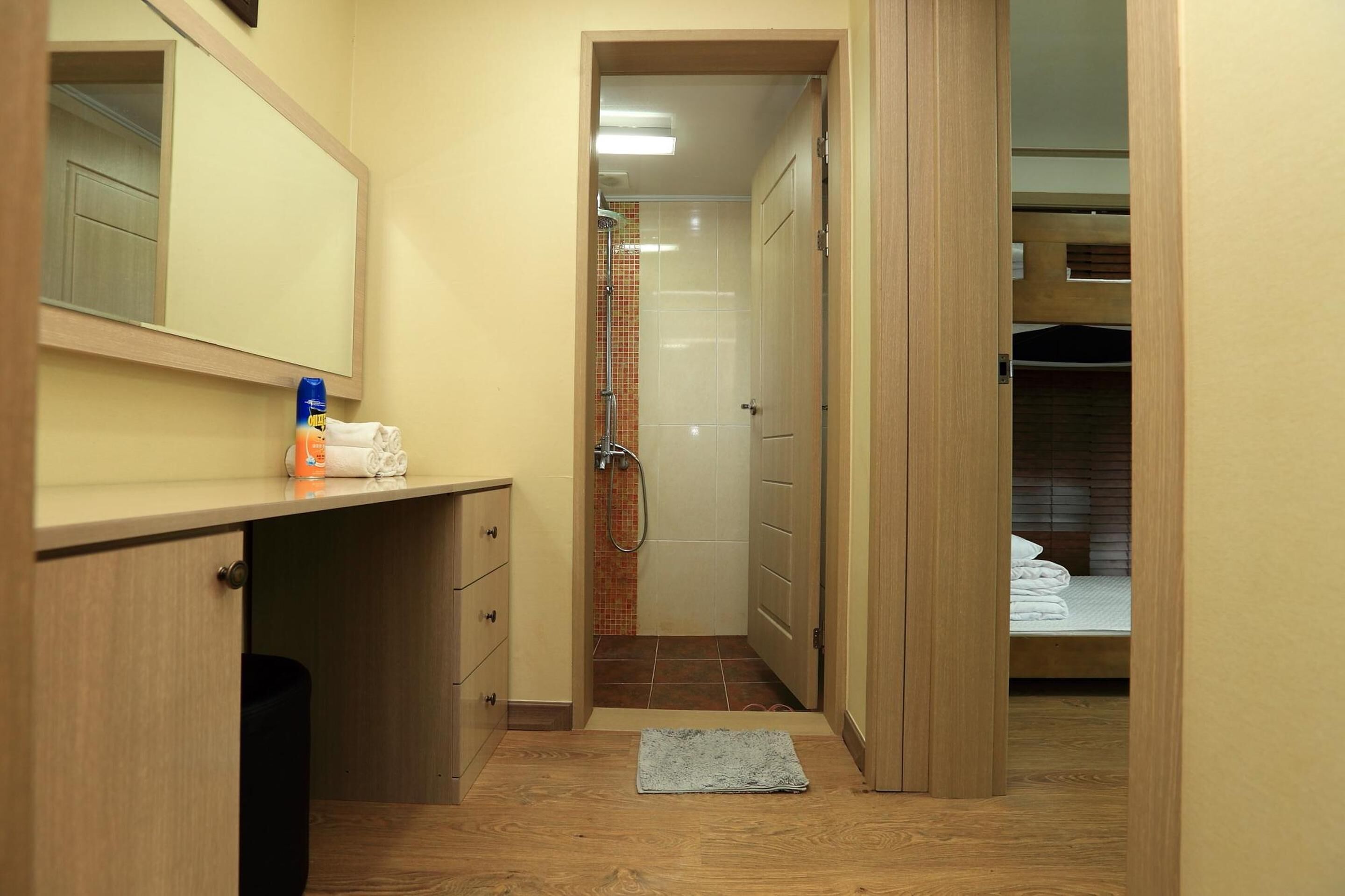 A compact bathroom with a shower, a mirror, and a wooden vanity with a towel and toiletries.