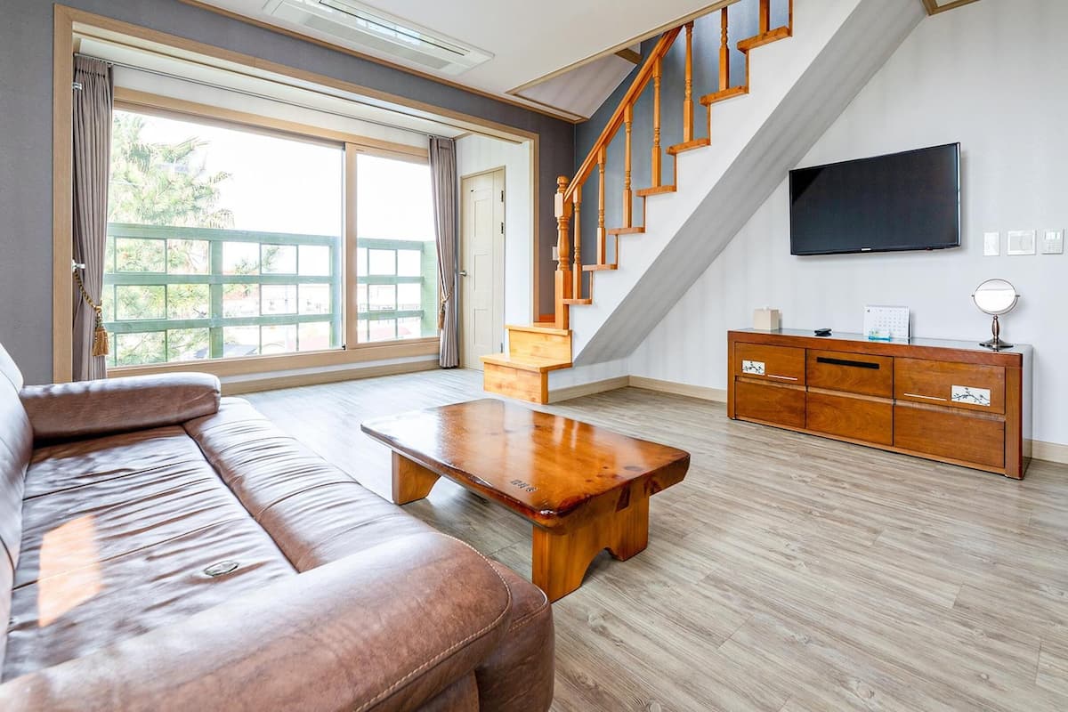 Un salon spacieux avec un escalier en bois, un téléviseur à écran plat et un meuble en bois.