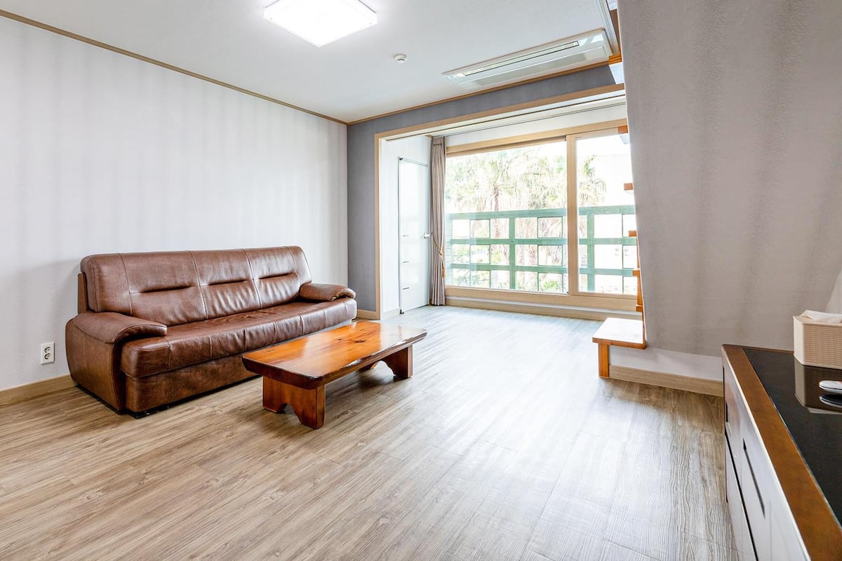 Un salon spacieux avec un canapé en cuir marron et une table basse en bois.
