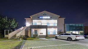 A two-story building with a modern design, a car parked in front, and a well-lit entrance.