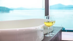A bathtub with two glasses of white wine on a wooden ledge. - Geoje Rockspa Pension (Geoje)
