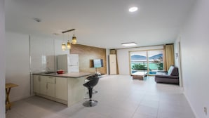 A modern kitchen with a central island, a dining area with a sofa, and a large window offering a scenic view. - Geoje Rockspa Pension (Geoje)
